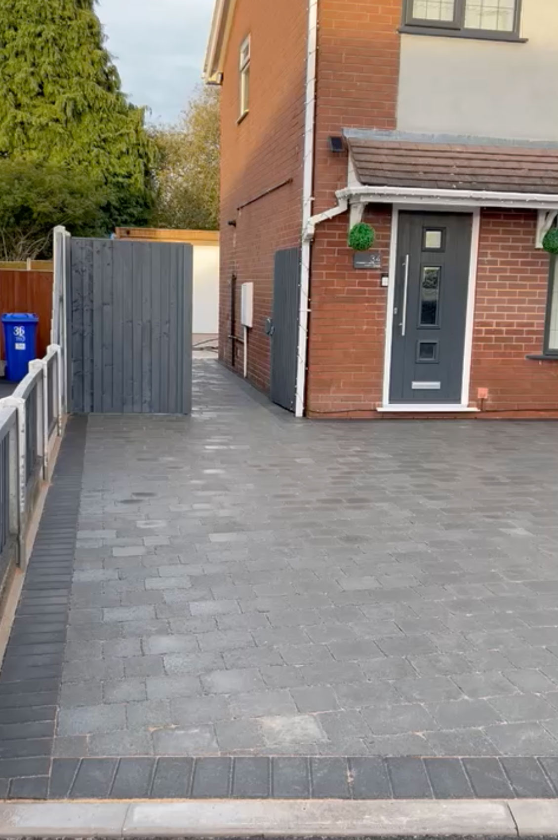 Charcoal block paving with a contrasting border at a red brick semi
