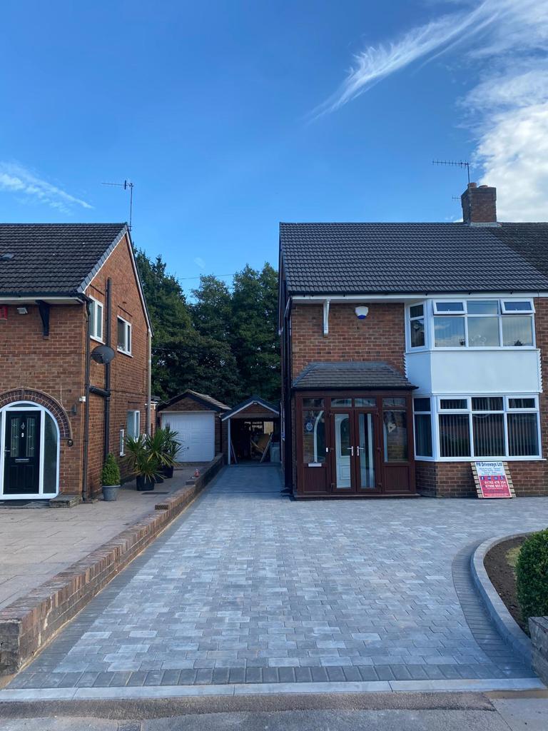 Silver grey block paved driveway running to a garage