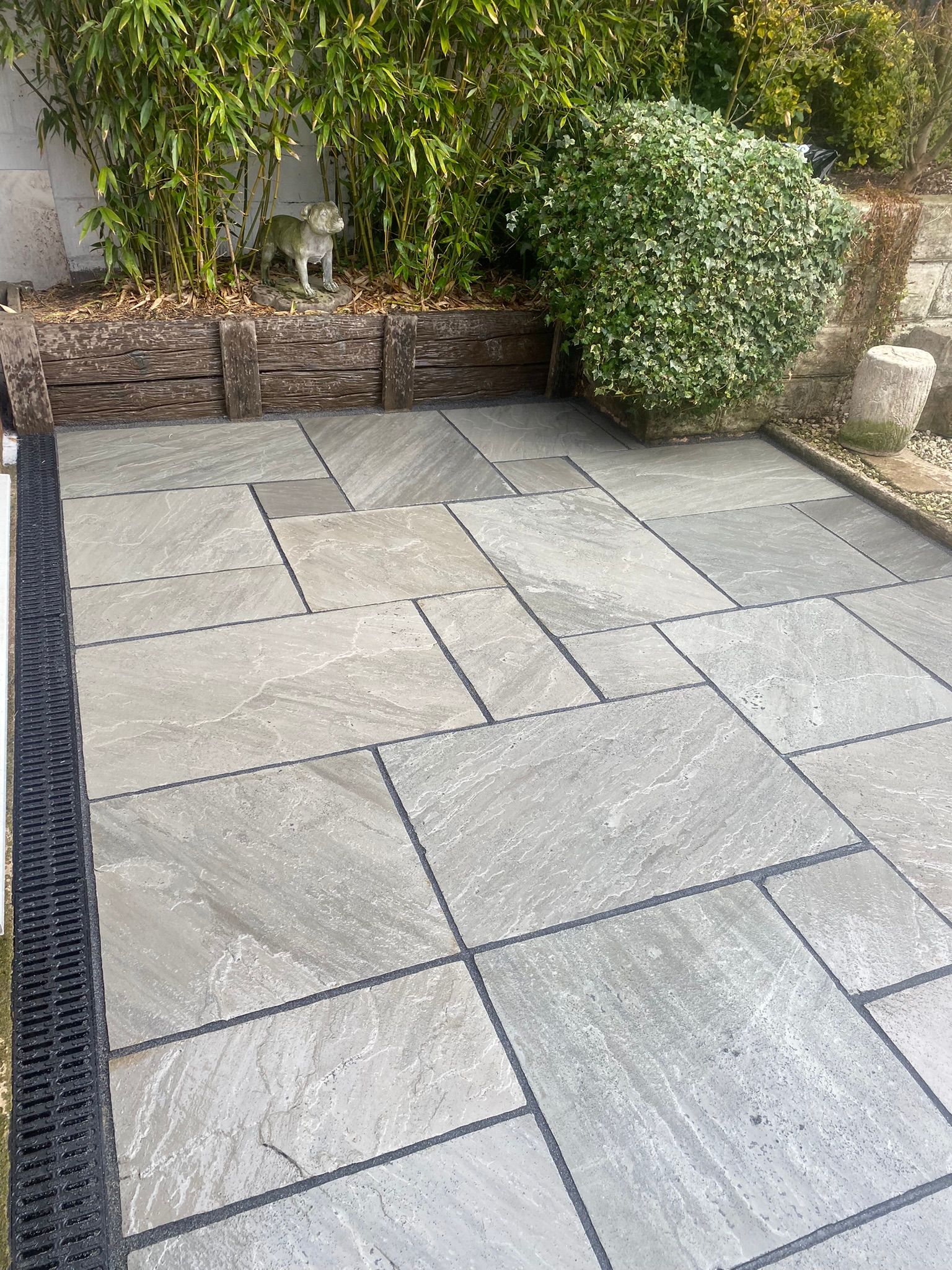 Indian sandstone patio with a sett border and channel drainage